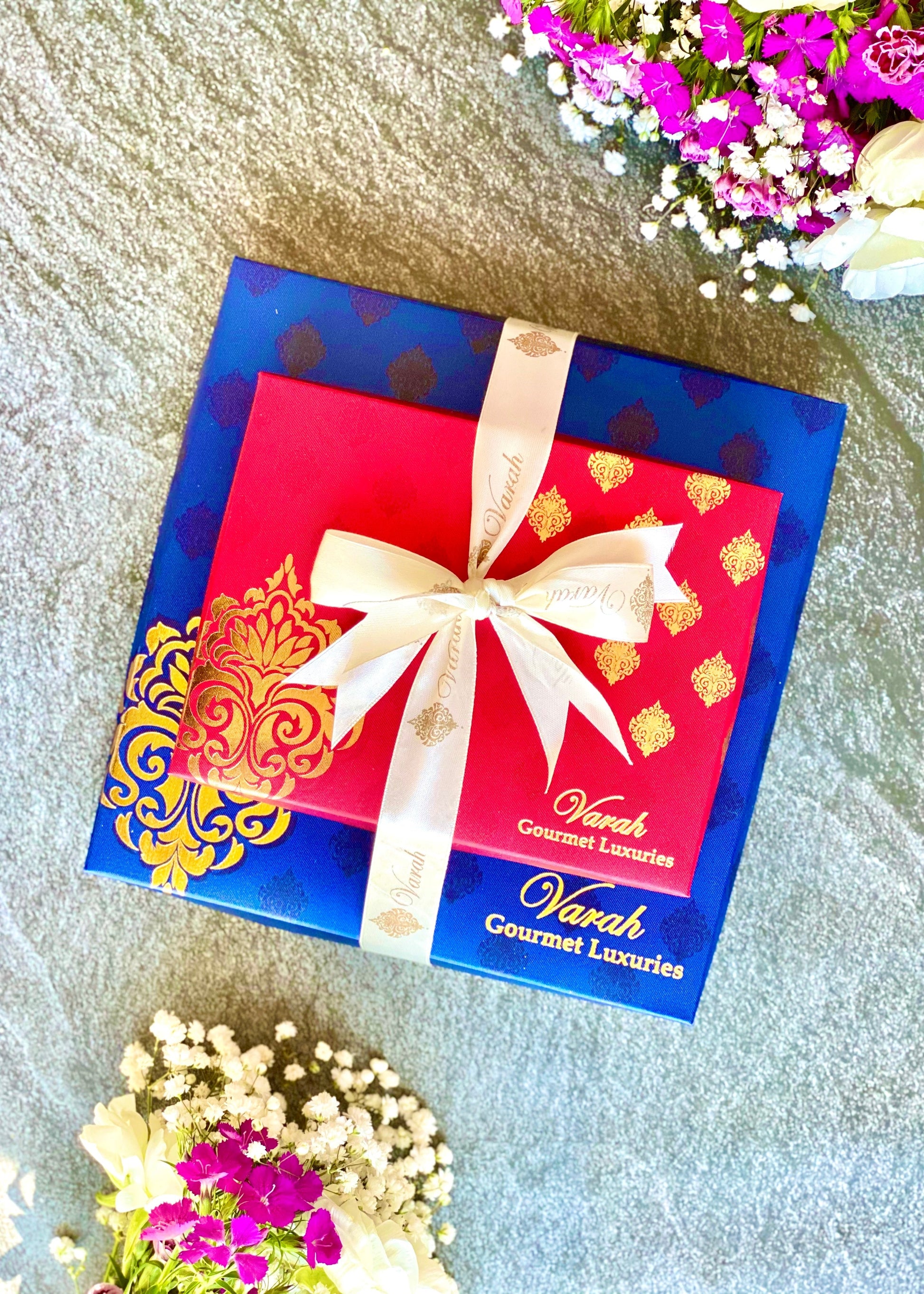 Rakshabandhan Gourmet Gifts in gold foiled boxes with a raw silk finish, wrapped in satin ribbon and with a Happy Rakhi lasercut